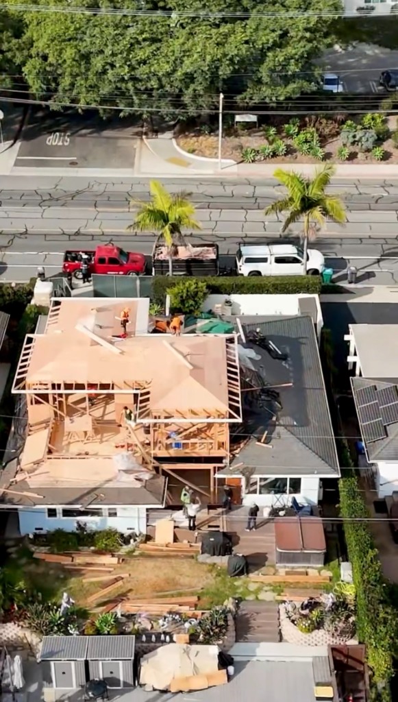 Aerial view of a home addition with crew and company trucks on site